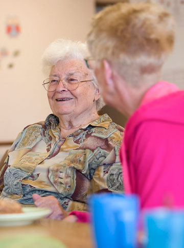 Freundlich schauende Bewohnerin mit Pflegekraft